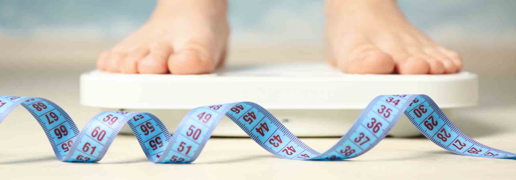 Standing on a weighing scale and with a tape measure 