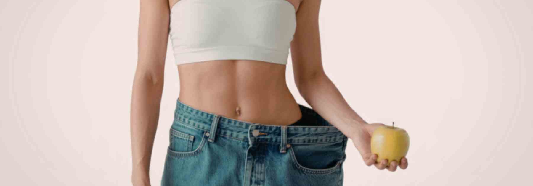 Woman showing off weight loss in jeans with an apple
