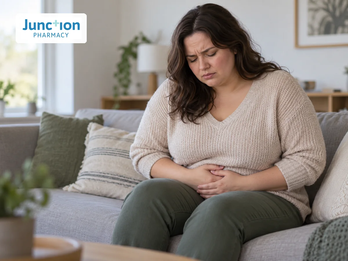 Woman holding her lower abdomen and looking uncomfortable at home